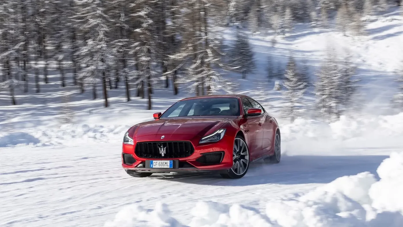 Red sixth-generation Maserati Quattroporte driving on a snow-covered road